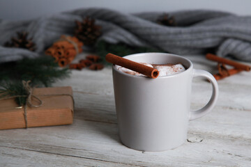 Hot chocolate, cinnamon, grey plaid, fir tree branches, cones, candy canes , craft gift wrap on white wooden table. Winter and Christmas concept. Spicy cocoa, New Year, closeup, copy space, side view