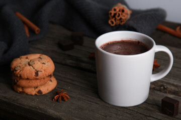 Mug and pieces of chocolate, spices, cookies, grey knitted scarf on rustic wooden table. Winter drink concept. Spicy cocoa, bakery, menu, top view, copy space