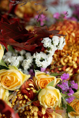 Fragment of a bright autumn bouquet in yellow-orange tones with roses and chrysanthemums on a black background.