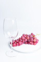 Red grapes and glass. Wine grapes on a white background.