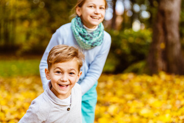 Activities in the fall concept. Cute little boy and girl running in autumn leaves.