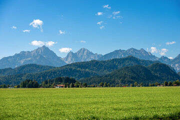 Green Agricultural Fields and Bavarian Alps with the small town of Schwangau near Fussen, Ostallgau, Bavaria, Germany.