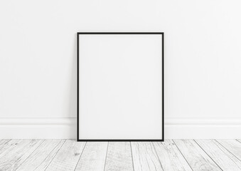 Vertical black frame mockup. Black frame poster on clean white wall and white wooden floor.
