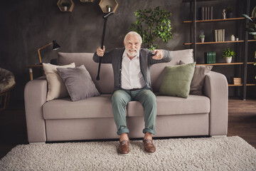 Photo of furious pensioner wear grey cardigan sitting couch holding remote trying find favorite tv show indoors house flat