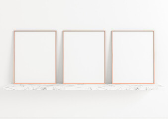 Three vertical rose gold frame mockups. Rose Gold frame poster on a marble shelf and clean white wall.