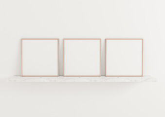Three square rose gold frame mockups. Rose Gold frame poster on a marble shelf and clean white wall.