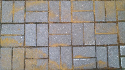 Obraz premium Sand on the paving stone. The road is paved with paving stones. On the way, sand is scattered in a thin layer, which in combination with the structure of the masonry creates an abstract pattern. Clean