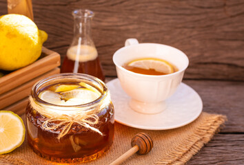 Honey in a glass jar with lemon on wooden background