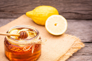 Honey in a glass jar with lemon on wooden background