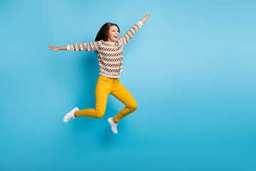 Full length photo of carefree young lady wear ornament sweater jumping hands arms sides isolated blue color background
