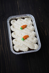 Carrot cake and cream cheese in an aluminium container. Wooden background.
