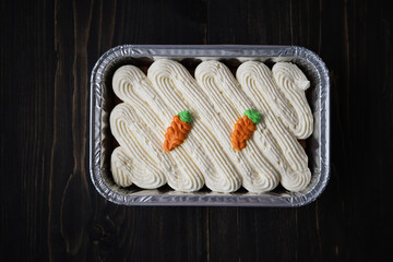 Carrot cake and cream cheese in an aluminium container. Wooden background.