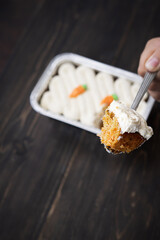 Carrot cake and cream cheese in an aluminium container. Wooden background.
