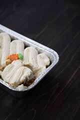 Carrot cake and cream cheese in an aluminium container. Wooden background.