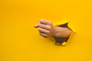 Woman's fist through broken yellow paper
