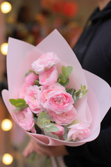 Young man florist holding big beautiful blossoming mono bouquet of pink ranunculus clooney hanoi flowers.