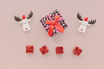 Christmas decoration with present box on pink background. Funny deer, cute small red gifts, new year concept. 