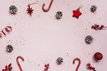 Collection of red Christmas objects as frame flat lay on pink background. Copy space.