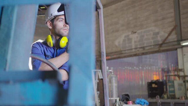 Concentrated forklift caucasian driver operating machine and holding hand on steering wheel  radio comminication operate teamwork with transportation of goods cargo in factory warehouse workshop.