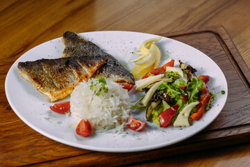 dorado fish fillet with garnish on a plate and wooden table