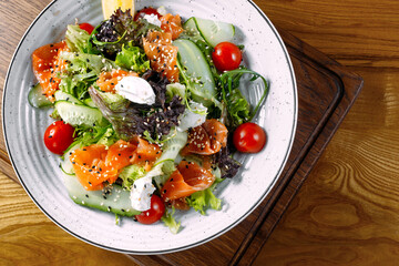 
italian vegetarian salmon salad cucumber vegetables on plate and wood