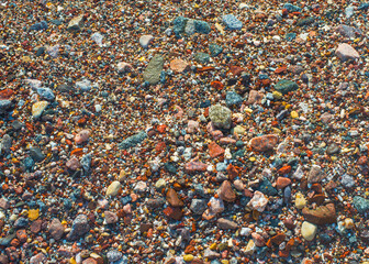 Wet colored pebbles on a beach in the surf