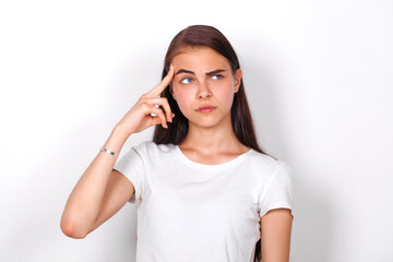 pensive young woman stands against white wall background