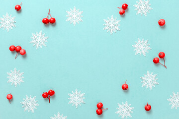 Xmas background white. Red berry, white snowflakes in shape frame on pastel blue background for greeting card. Flat lay, top view, copy space.