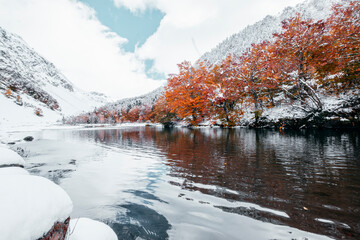 small lake next to the Saut Deth Pish waterfall during autumn and a snowy day, located in the aran...