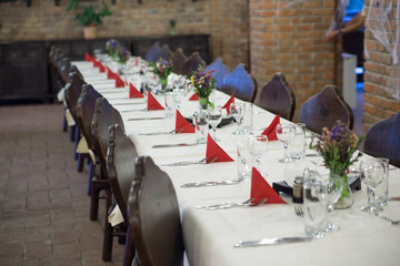 Big table with wooden chairs , inside a restaurant prepared for the wedding guests.