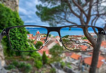Focused image of view of the small town Omis surrounded with mountains, Cetina river and sea, Makarska Riviera, Croatia. Better vision concept. Focused image in eyeglasses. - obrazy, fototapety, plakaty