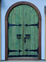 Wooden double barn door with rounded corners. Wooden plank door with forged metal parts.