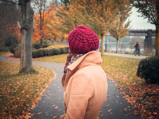 A woman with her back to camera wearing fall fashion clothes surround by autumn colours in a park in Preston, UK