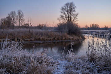 Breath of winter, first ice on the lake, dawn on a frosty morning with frost on the grass, close-up of frost, patterns on the first ice.