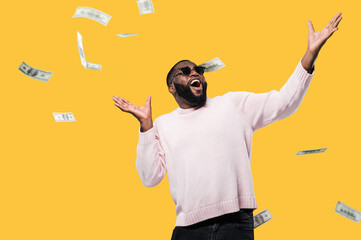 Cheerful happy african american man in sunglasses look up at falling money, winning lottery...