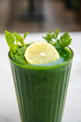 A glass of raw organic healthy green detox juice smoothie drink. Detox juice with parsley, mint and sliced lemon vegetables.