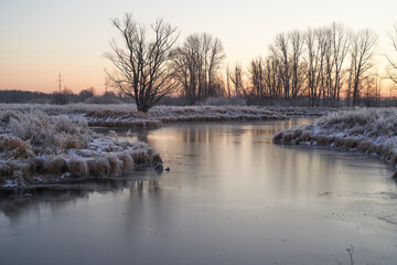 Breath of winter, first ice on the lake, dawn on a frosty morning with frost on the grass, close-up of frost, patterns on the first ice.