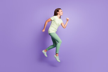 Fototapeta na wymiar Full body profile portrait of attractive lady jumping running light green clothing isolated on purple color background