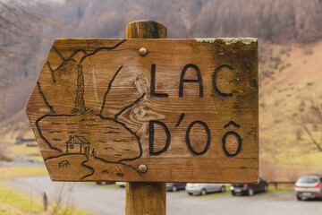 Wooden direction sign to the Lake d'Oô at the Valley Val d’Astau, southwest of Bagneres de Luchon in the French Pyrenees. The trail to Lake d'Oô, Haute-Garonne, France.