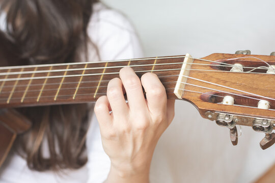 Closeup photograph of hand playing a chord on guitar, white background