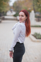 Fototapeta premium Beautiful and cute red-haired girl with pleasure posing on the street