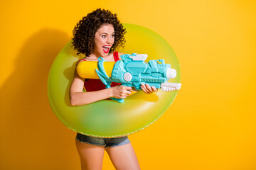 Photo of pretty playful curly hairstyle girl lady model have great time friends trip sea spray water gun wear green float circle trendy outfit isolated yellow color background