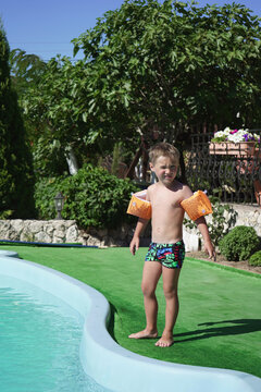 Little Boy In Inflatable Headbands Is About To Jump Into The Pool.