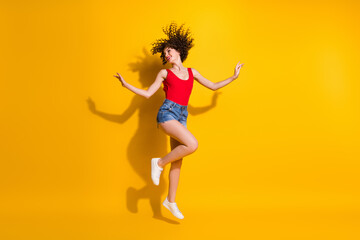 Fototapeta na wymiar Full length body size photo of pretty female hipster with afro curly hairstyle jumping dancing cheerfully smiling pretending ballerina playing isolated over vivid yellow background