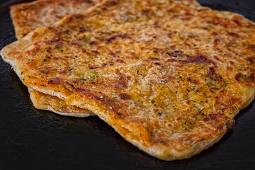 Traditional Moroccan Msemen Farci with Chicken, Peppers and Onions on Dark Background.