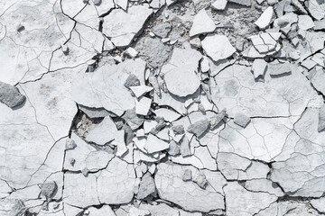 Cracked concrete texture background. Grey surface with cracks close up. A lot of pieces of splintered plaster. Abstract concept of split, dissent, disagreement, discord. Sunny day with shadows.
