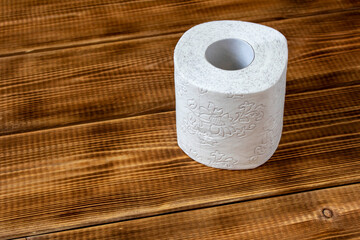 A roll of toilet paper on a wooden table. Close up.