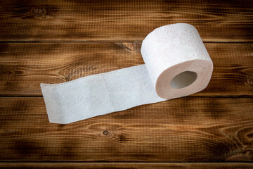 A roll of toilet paper on a wooden table. Close up.