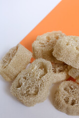 Closeup loofah sponges in orange background. - obrazy, fototapety, plakaty
