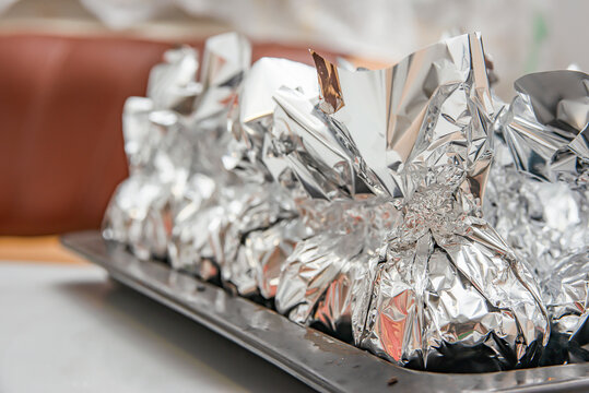 Several potatoes in foil lie on the table.